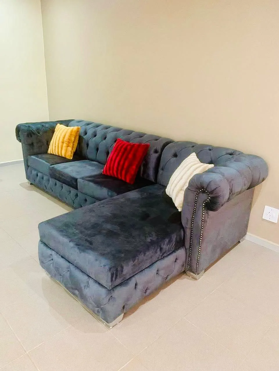 Grey velvet Chesterfield corner sofa with deep button tufting and scatter cushions